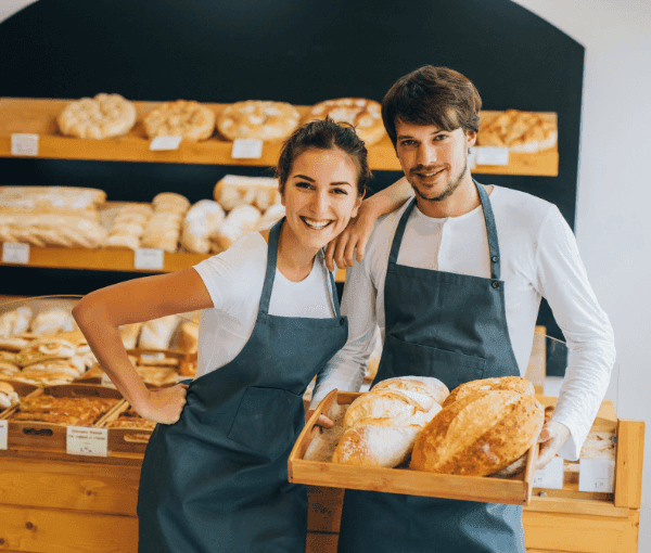 Two bakers standing in front of bread with Bakery Workers' Compensation Insurance