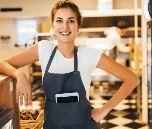 A woman in a bakery smiling because she has Essential Bakery Insurance